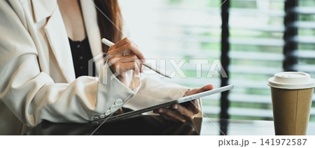 Young businesswoman in formal wears using digital tablet in modern office 141972587