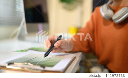 Graphic Designer Reviewing Color Swatches with Stylus Pen at Creative Workspace 141972588
