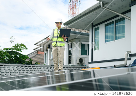 Engineer Inspecting Solar Panels on Residential Rooftop with Laptop 141972626