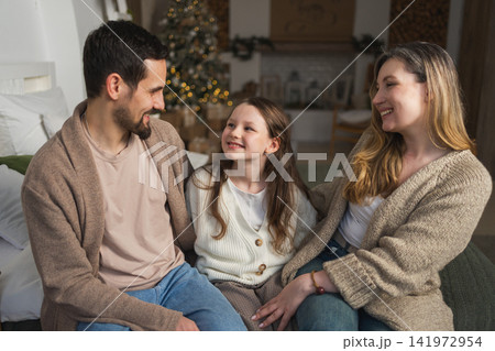 Merry Christmas Xmas. Happy family mother father daughter kid near Christmas tree at home. Parents little girl celebrating Christmas New Year enjoying winter holidays together. Family moments at home Merry Christmas Xmas. Happy family mother father daughter kid near Christmas tree at home. Parents little girl celebrating Christmas New Year enjoying winter holidays together. Family moments at home 141972954