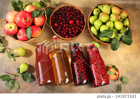 Apples, pears and cherries in baskets with bottles of cider, compote, and mulled wine, a Thanksgiving backdrop and a rustic harvest, concept of healthy natural food and home canning, 141973181