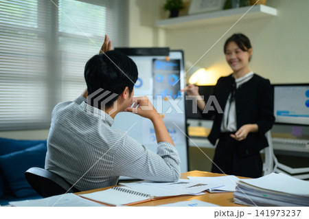 Asian Businesswoman Presenting Data Charts to Colleague in Modern Office Meeting Asian Businesswoman Presenting Data Charts to Colleague in Modern Office Meeting 141973237