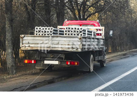 The car transports metal round pipes in the back, freight The car transports metal round pipes in the back, freight 141973436
