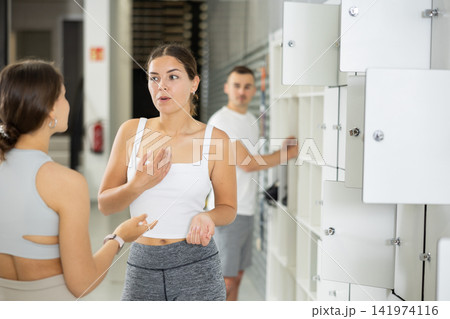Two young women talking in locker room Two young women talking in locker room 141974116