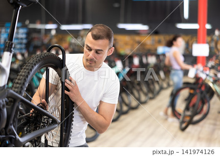 Young man choosing bike in store Young man choosing bike in store 141974126