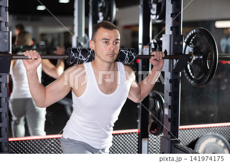 Young man training with barbell in gym 141974175