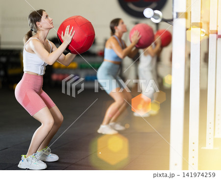 Athletic woman in sportswear training with ball in gym 141974259