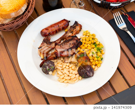 Lamb ribs on bone, sausage, piece of black pudding are complemented with stewed beans Lamb ribs on bone, sausage, piece of black pudding are complemented with stewed beans 141974309