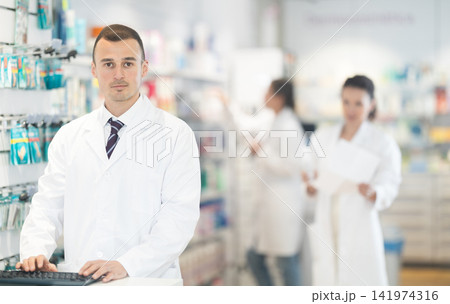 Portrait of friendly male pharmacist at the cash register in pharmacy 141974316