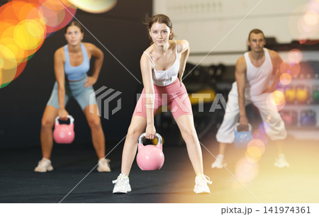 Young woman lifting kettlebell in gym Young woman lifting kettlebell in gym 141974361