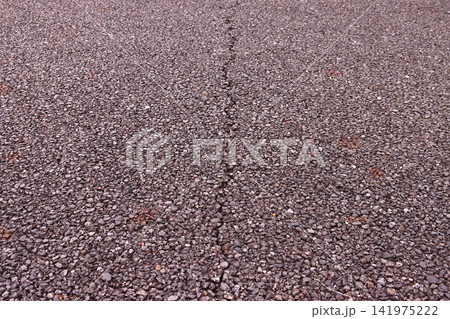 経年劣化で中央に一筋のひび割れが入ったアスファルト道路 経年劣化で中央に一筋のひび割れが入ったアスファルト道路 141975222