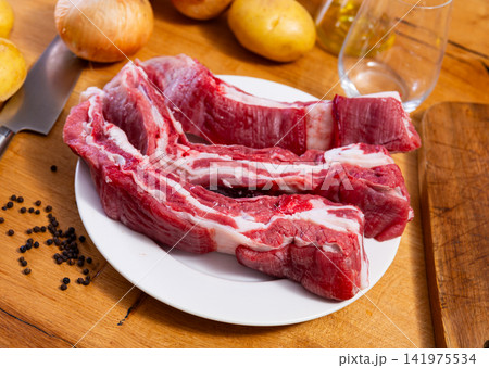 Raw beef ribs on the kitchen table along with other ingredients for making delicious lunch or dinner Raw beef ribs on the kitchen table along with other ingredients for making delicious lunch or dinner 141975534