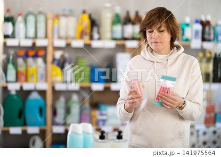Woman carefully selects razor for shaving in the household goods department of supermarket 141975564