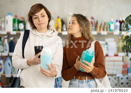 Two women checking expiration date of shampoo or shower gel using her smartphone in supermarket Two women checking expiration date of shampoo or shower gel using her smartphone in supermarket 141976610