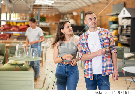 Spouses look for something in furniture store, searching for perfect item to complete patio Spouses look for something in furniture store, searching for perfect item to complete patio 141976616