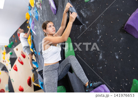 Young woman practicing rock climbing on climbing wall Young woman practicing rock climbing on climbing wall 141976653