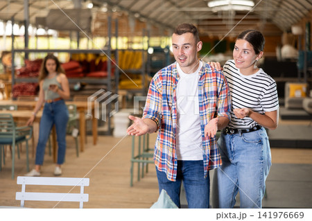 Spouses look for something in furniture store, searching for perfect item to complete patio Spouses look for something in furniture store, searching for perfect item to complete patio 141976669