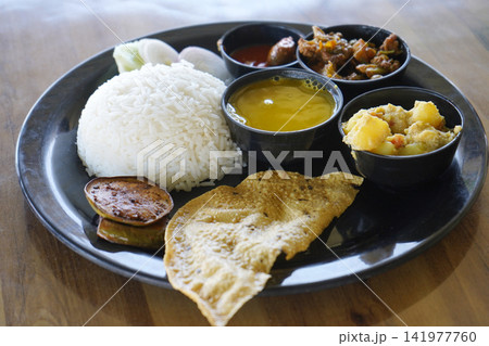 Authentic Indian Bengali vegetarian thali meal platter with rice dal and curries on a black plate Authentic Indian Bengali vegetarian thali meal platter with rice dal and curries on a black plate 141977760