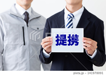 提携のホワイトボードを持つスーツを着た若い男性ビジネスマンと作業着のミドル男性 提携のホワイトボードを持つスーツを着た若い男性ビジネスマンと作業着のミドル男性 141978091