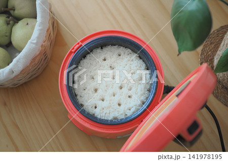 Cooked rice in a rice cooker on a wooden table Cooked rice in a rice cooker on a wooden table 141978195