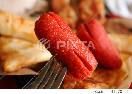 Hot dogs on a fork with side dishes on a plate 141978196