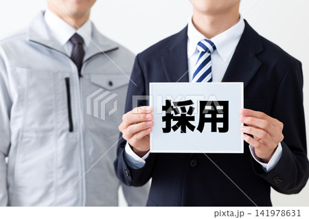 採用のホワイトボードを持つスーツを着た若い男性ビジネスマンと作業着のミドル男性 採用のホワイトボードを持つスーツを着た若い男性ビジネスマンと作業着のミドル男性 141978631