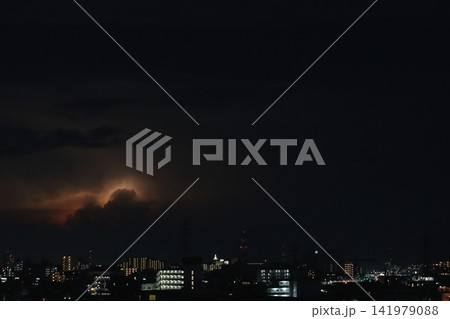 ゲリラ雷雨 雷に照らされる発達した積乱雲と都市の夜景 141979088