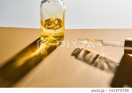 Small Glass Vial With Dropper And Golden Oil Casting Sharp Shadows On Warm Tan Surface Small Glass Vial With Dropper And Golden Oil Casting Sharp Shadows On Warm Tan Surface 141979799