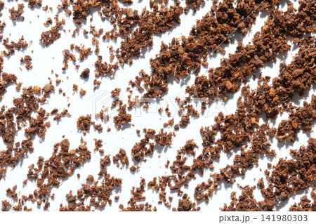 Ground Coffee Granules Scattered In Diagonal Pattern On White Surface Closeup Revealing Texture Ground Coffee Granules Scattered In Diagonal Pattern On White Surface Closeup Revealing Texture 141980303