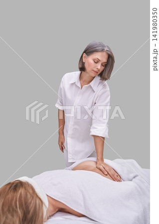Female Therapist Pressing Lower Back Of Prone Client During Massage Session On Treatment Table Female Therapist Pressing Lower Back Of Prone Client During Massage Session On Treatment Table 141980350