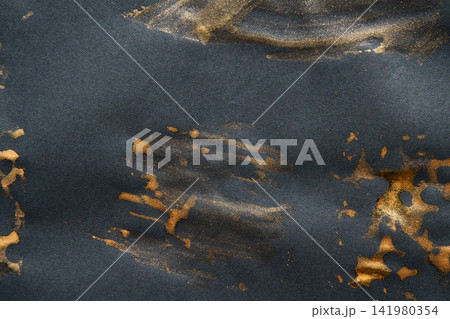 Gold Pigment Streaks And Smudges On Dark Paper Creating Brushed Metallic Texture And Scattered Gold Pigment Streaks And Smudges On Dark Paper Creating Brushed Metallic Texture And Scattered 141980354