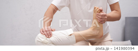 Therapist Holding Client Foot And Guiding Assisted Stretch While Client Lies On Mat With Neutral 141980394