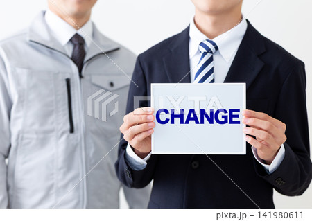 CHANGEのホワイトボードを持つスーツを着た若い男性ビジネスマンと作業着のミドル男性 CHANGEのホワイトボードを持つスーツを着た若い男性ビジネスマンと作業着のミドル男性 141980611