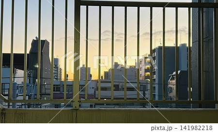 金網フェンス越しに広がる都市の夕焼け空とシルエット 金網フェンス越しに広がる都市の夕焼け空とシルエット 141982218