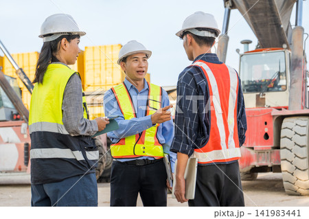 Construction team discussing project details on site for safety compliance. 141983441