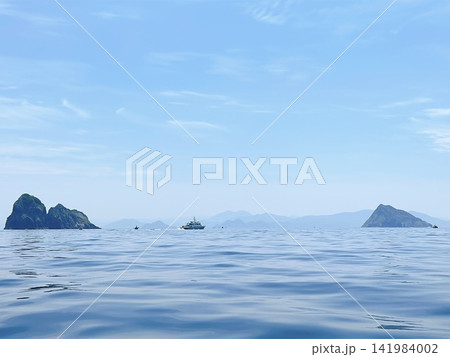 青空と穏やかな青い海に浮かぶ島々と航行する船の風景 141984002