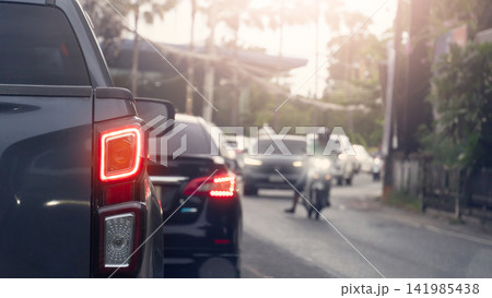 Rear view of pickup car with turn on brake light. Multiple vehicles stopped in heavy traffic on a city street during a busy daytime commute. Were a cars and motorcycles with their headlights on. Rear view of pickup car with turn on brake light. Multiple vehicles stopped in heavy traffic on a city street during a busy daytime commute. Were a cars and motorcycles with their headlights on. 141985438