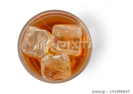 Refreshing glass of iced beverage shimmering under warm light with large ice cubes Refreshing glass of iced beverage shimmering under warm light with large ice cubes 141986647