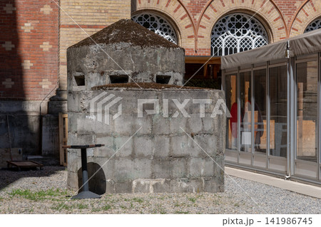 Historic concrete bunker structure standing in courtyard beside brick building Historic concrete bunker structure standing in courtyard beside brick building 141986745