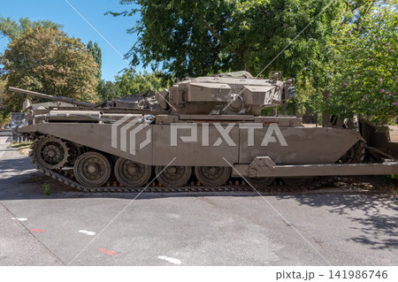 Side view of military tank displayed outdoors under leafy trees 141986746