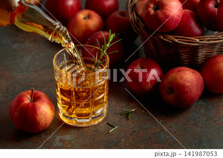 Apple juice is poured from a bottle into a glass. Apple juice is poured from a bottle into a glass. 141987053