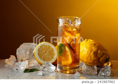 Classic iced black tea in tall glass with lemon wedges, ice cubes and mint leaves. Classic iced black tea in tall glass with lemon wedges, ice cubes and mint leaves. 141987062