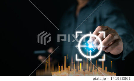 A person interacts with a glowing digital target interface above rising data bars, highlighting analytics precision and modern strategy in a dark tech focused setting boosting future tech growth. A person interacts with a glowing digital target interface above rising data bars, highlighting analytics precision and modern strategy in a dark tech focused setting boosting future tech growth. 141988861