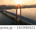Traffic flows over red bridge as the golden sunset glows off the Qiantang River and the urban skyline. 141990422