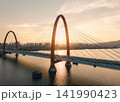Traffic flows over red bridge as the golden sunset glows off the Qiantang River and the urban skyline. 141990423