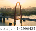Golden sunset over Hangzhou Qiantang River bridge, with traffic crossing and city skylines reflecting on the water 141990425