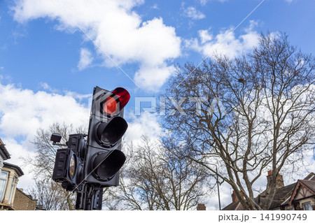 Red traffic light showing stop against blue sky Red traffic light showing stop against blue sky 141990749