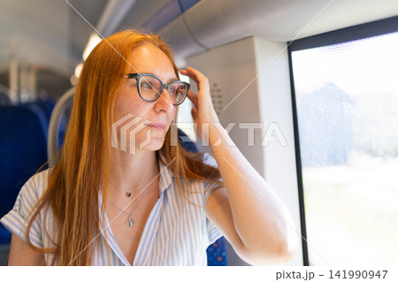 Young woman traveling on train looking out window 141990947