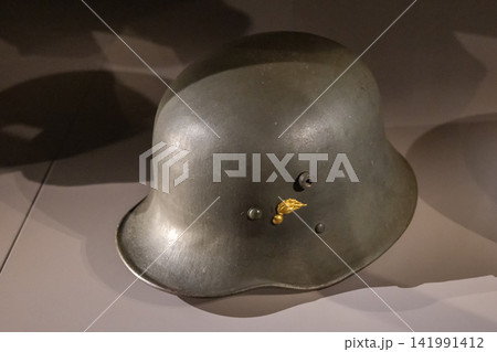 Historic metal helmet of the Austrian Gendarmerie with distinctive golden insignia displayed as part of a museum collection. 141991412