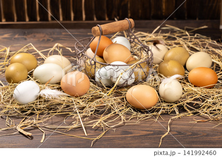 Fresh organic eggs in straw and wire basket Fresh organic eggs in straw and wire basket 141992460
